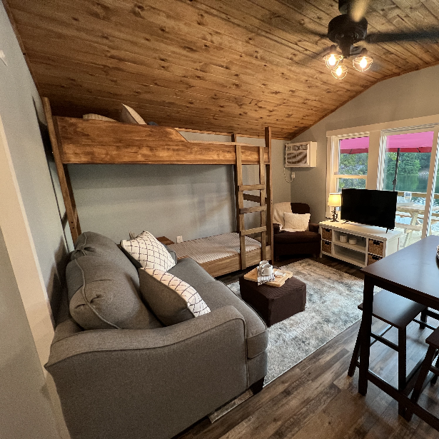 Wooden ceilings, wood bunkbed and hardwood floors in a modern tiny house’s living space.