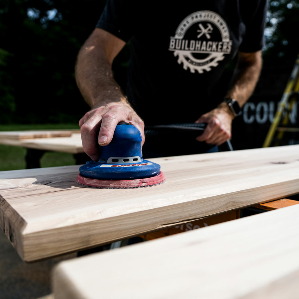 Sanding down a piece of lumber onsite at Renovation Hunters’ mobile home renovation.